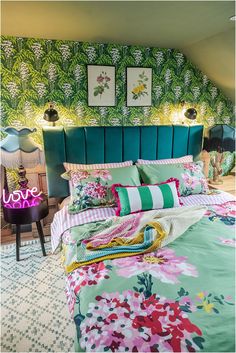 a bedroom with green and pink bedding in the corner next to a night stand