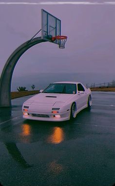 a white car parked in front of a basketball hoop