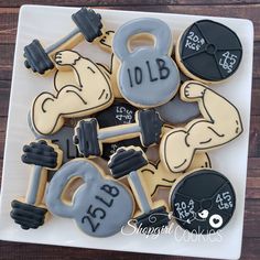 decorated cookies with the words bodybuilding and dumbbells are on a white plate