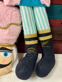 a stuffed animal is sitting next to a doll's legs and leg wearing boots