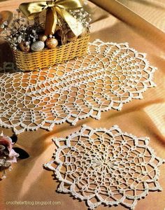 two crocheted doily sitting on top of a table next to a basket