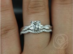 a woman's hand with a diamond ring on top of her wedding band and an engagement ring in the middle