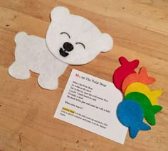 a polar bear next to a rainbow fish on a wooden table with a poem about the polar bear