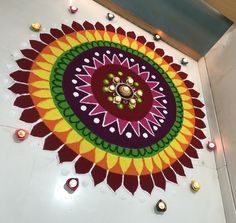 a colorful flower design on the floor with candles around it