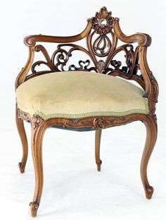 an ornate wooden chair with a beige upholstered seat and back cushion, on a white background