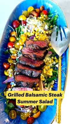 a blue plate topped with steak, corn and tomato salad next to a silver fork