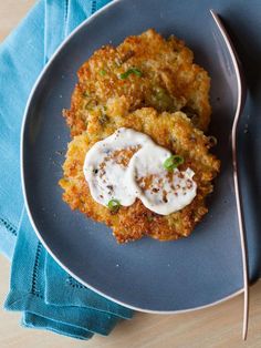 two crab cakes on a blue plate with a fork next to it and a napkin