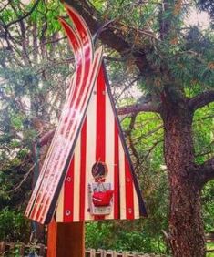 an upside down birdhouse in the shape of a flag hanging from a tree branch