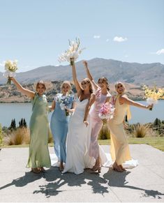 four bridesmaids holding bouquets in their hands and posing for the camera with mountains in the background