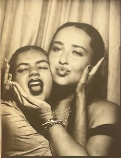 an old black and white photo of two women posing for the camera with their mouths open