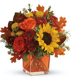 an orange vase filled with autumn flowers and leaves