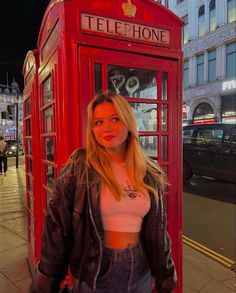 a woman standing in front of a red phone booth