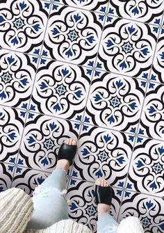 a person standing in front of a black and white tile wall