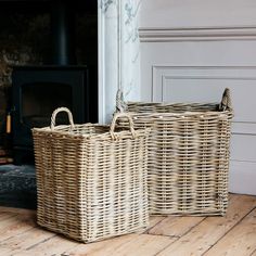 two wicker baskets sitting on the floor in front of a fireplace