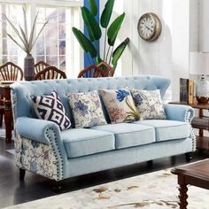 a living room with blue couches and wooden tables in front of a large window