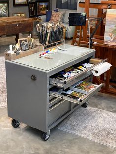 an art studio with lots of paint and brushes on the table in front of it