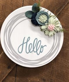 a sign that says hello with some flowers on top of it and the word hello written in cursive writing