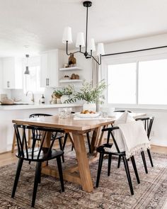 a dining room table with four chairs and a rug on the floor in front of it