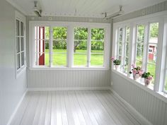 an empty room with white walls and wood flooring, two windows are open to the yard