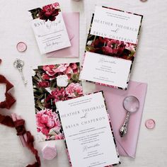 the wedding stationery is laid out with pink flowers