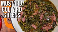 a bowl filled with meat and greens on top of a wooden table next to a red pot