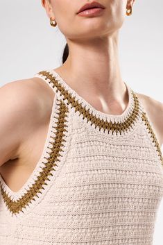 a woman in a crocheted tank top with gold hoop earrings on her head