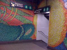 an empty subway station with colorful mosaic tiles on the wall and stairs leading up to it