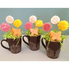 three coffee mugs filled with candy and flowers