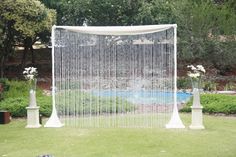 an outdoor wedding ceremony setup with white drapes and flowers in vases on the grass