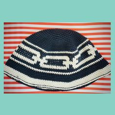 a crocheted hat on top of a red and white striped table cloth with the word nerd written across it