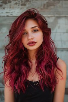 Young woman with vibrant red hair and freckles standing against a textured wall. Layered Haircuts For Heart Shaped Face, Long Layered Hair Heart Shaped Face, Face Framing Layers Heart Shaped Face, Shag Haircut For Heart Shaped Face, Wavy Hair Heart Shaped Face