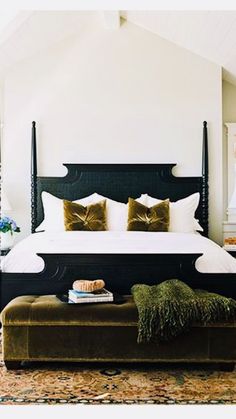 a bedroom with a large bed and pillows on the headboard, along with a bench