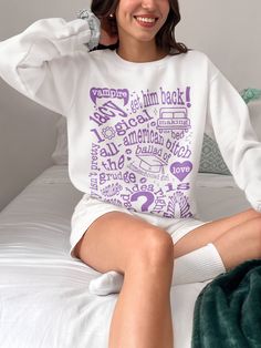 a woman sitting on top of a bed wearing a white shirt with words all over it