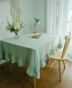 a green table cloth with ruffled edges sits on a wooden chair in front of a window