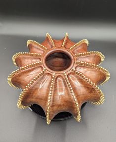 a wooden vase with gold beading on the edges and an open hole in the middle