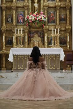 a woman sitting in front of a church alter wearing a pink dress and looking down at the floor