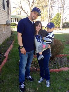 a man, woman and child standing in front of a house