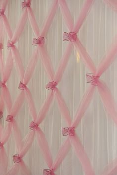 pink sheer curtains with bows hanging on them