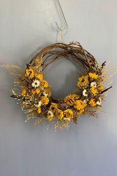 a wreath hanging on the wall with yellow and white flowers in it's center