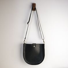 "With a classic saddle bag shape and convenient, magnetic snap closure, this is your new go-to bag. Easily fit everyday items including wallets, keys, phone, and more. We hand-cut buttery soft yet durable 5 oz Horween leather and stitch it with heavyweight nylon thread. The crossbody straps are available in multiple color options and are fitted with solid brass hardware. * Approximately 10\" x 10\" x 2\" * Crossbody strap drop adjusts from 16\" - 28\" * Magnetic snap closure * Unlined interior" Classic Saddle Bag With Adjustable Strap For On-the-go, Classic Crossbody Saddle Bag For On-the-go, Rectangular Saddle Bag With Magnetic Closure For Daily Use, Everyday Saddle Flap Bag With Adjustable Strap, Everyday Use Saddle Flap Bag With Adjustable Strap, Everyday Saddle Bag With Detachable Strap, Modern Saddle Bag With Magnetic Closure For Daily Use, Classic Saddle Shoulder Bag For Everyday, Daily Use Saddle Bag With Adjustable Strap