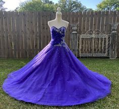 a purple ball gown on display in front of a fence