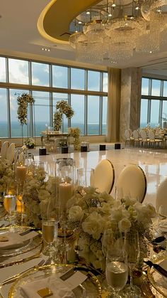 a table set up for a formal function with white flowers and candles on the tables