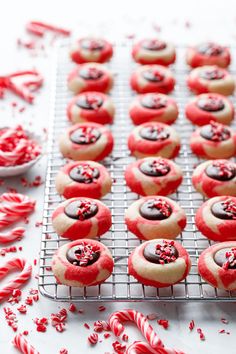 red and white decorated cookies on a cooling rack with candy canes around them, ready to be eaten