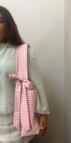 a woman wearing a pink and white gingham top with a bow on the back