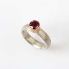 Gold, Silver & Stone Ring - Cradled in a 22k gold setting, a stunning 6.5mm pink garnet forms the focal point of this effortlessly elegant ring. The sterling silver band is finished with a scratch-brushed texture and has a curved interior for a comfortable fit on the finger. Garnet Ring Gold, Curved Interior, Silver Stone Ring, Pink Garnet, Rings Collection, Artful Home, Garnet Ring, Elegant Ring, Garnet Rings