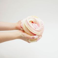 a hand holding a ball of pink and white icing