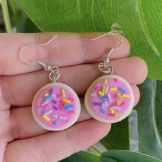 a pair of earrings with sprinkles on them in front of a plant