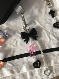 a cell phone is laying on top of a white sheet with black and pink charms