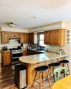 a kitchen with wooden cabinets and an island in front of a stove top oven next to two stools