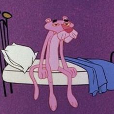 a pink cartoon cat sitting on top of a bed next to a night stand and lamp